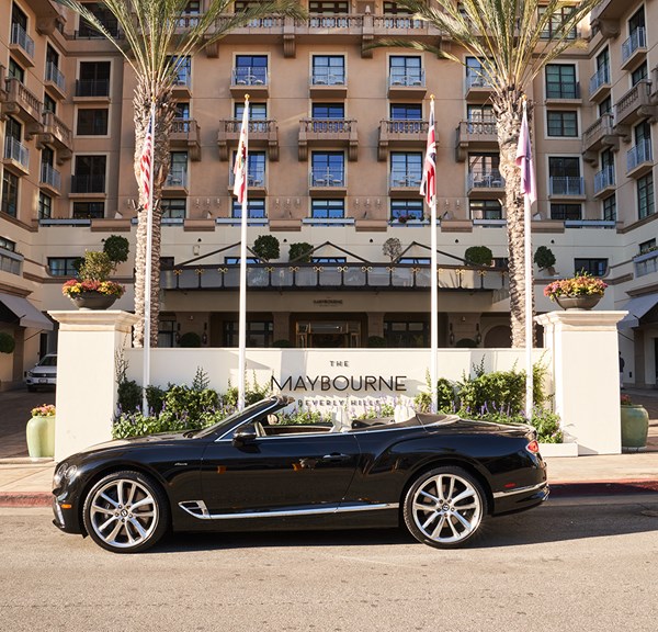 Black Bentley convertible parked in front of the exterior of The Maybourne Beverly Hills hotel