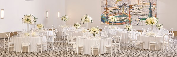 White table and round chairs laid up with dinner settings and flowers in the ballroom