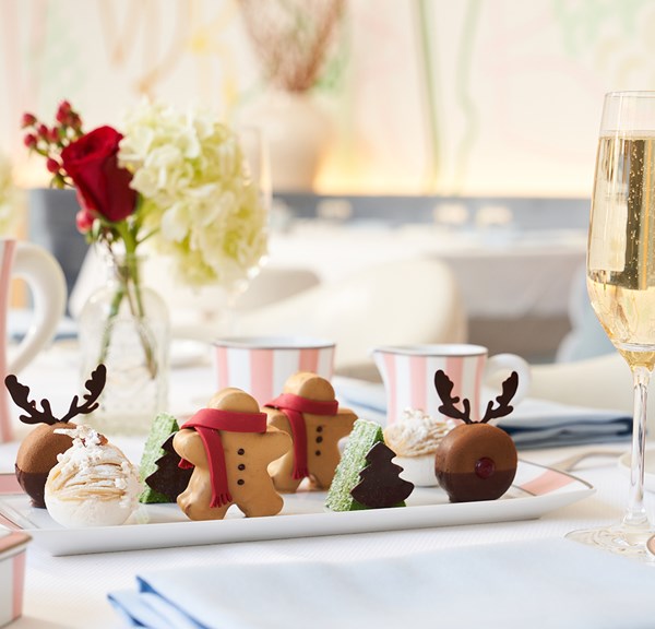 Winter holiday themed tea pastries with pink and white tea china on a white tablecloth