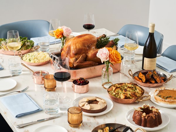 Thanksgiving feast on a table with turkey, side dishes, desserts and wine