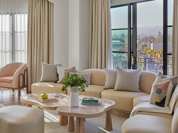 Curved couch and coffee table in hotel suite with sliding doors open to reveal a view of Beverly Hills