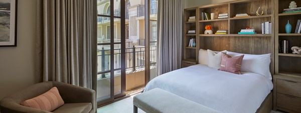 Guest bedroom with wooden panelled walls and open doors out to sunshine in The Residence